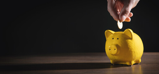 Male hand putting coin to piggy bank. Saving