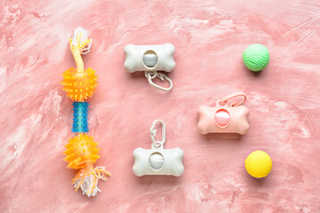 Different dispensers with pet waste bags and toys on color background