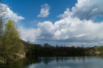 Bright skyline with puffy clouds over the lake and forest