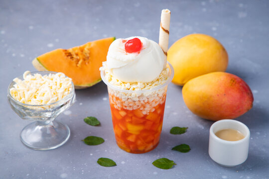 Mango And Melon Iced Drink With Decorated Ice Cream On A Gray Table