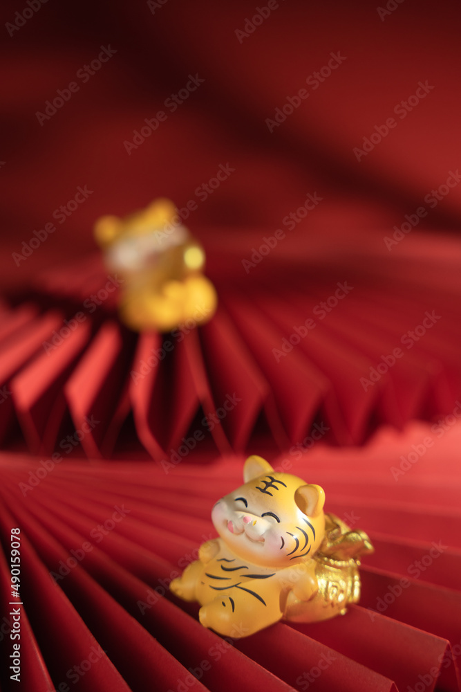 Sticker Vertical shot of a cute tiger figurine on a paper folding fan on red background