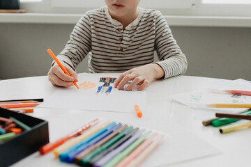 The boy draws with felt-tip pens