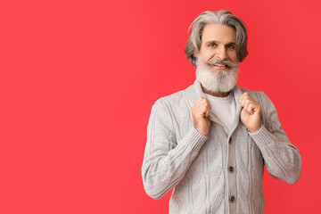 Handsome senior man in knitted sweater on red background