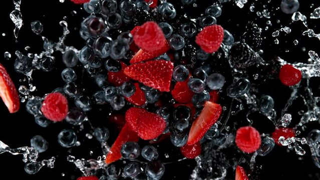 Super slow motion of rotating berries fruit with splashing water, black background. Filmed on high speed cinema camera, 1000 fps. Speed ramp effect.