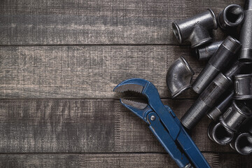 Cast iron pipes and fittings of different shape and forms, laying on a rustic wooden table