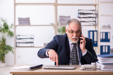 Naklejka premium Old male employee working at workplace