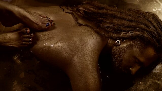 female feet on male back, lovers are bathing in golden water, sexuality and sensuality