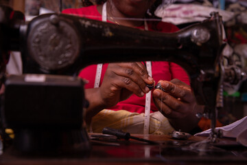Close-up of the hands of a working seamstress. African seamstress inside her tailor shop