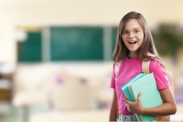 Happy cheerful smiling cute schoolgirl with backpack standing posing in classroom