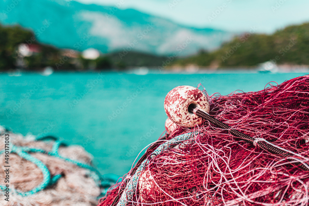 Poster shallow focus of a purple fishing net in port with blurred blue water and trees