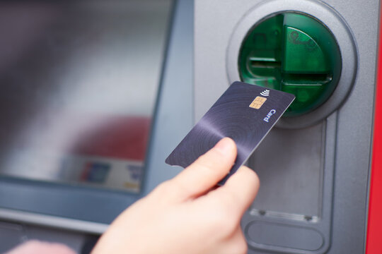 Close up of a hand holding credit card to withdraw money at the ATM.