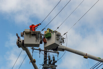 Low angle of  Lineworkers work on cranes to fix electric telephone poles