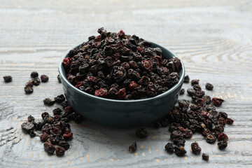 Dried black currants and bowl on grey wooden table
