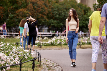 Woman in jeans in public park walks at daytime.