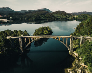 View of a bridge passing over water with forests and mountains in the background