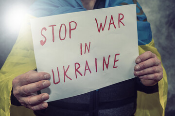 activist holding poster with text No War in Ukraine sign at a public demonstration