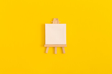 Easel on yellow background. Top view with copy space.