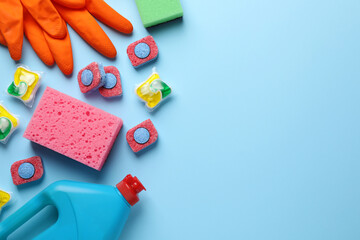 Flat lay composition with dishwasher detergent pods and tablets on light blue background, space for text