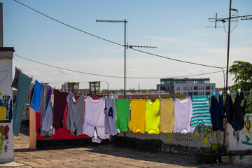 Colorful laundry hanging on clothes rope/string on flat rooftop of residential building. Concept of drying laundry outside, on hot and windy summer day. - Powered by Adobe