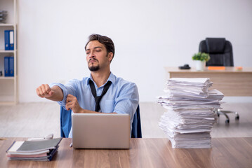 Naklejka premium Young male employee unhappy with excessive work in the office