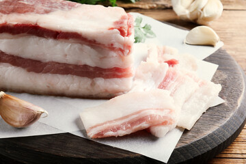 Tasty salt pork with garlic and parsley on wooden table, closeup