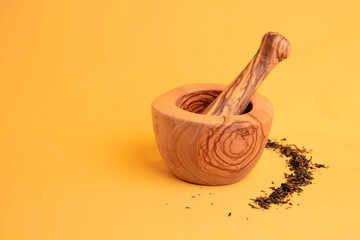 Closeup of herbs with a mortar and pestle with a yellow background