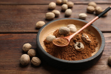 Nutmeg powder and seeds on wooden table