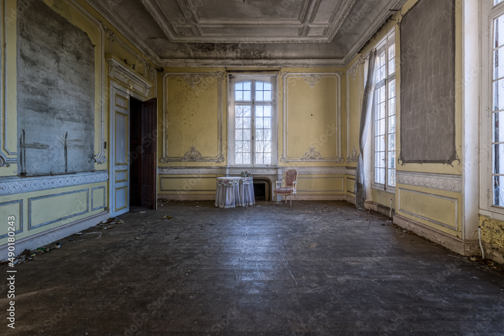Poster room of an abandoned building with only a table and a chair.