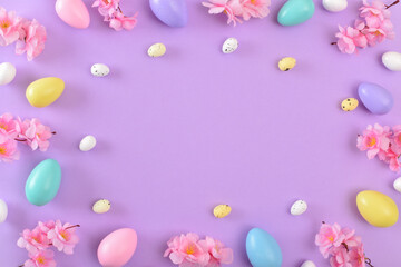 Background with Easter colored eggs on a purple background. Spring background for the Easter holiday. Copy space. Flat lay, top view.