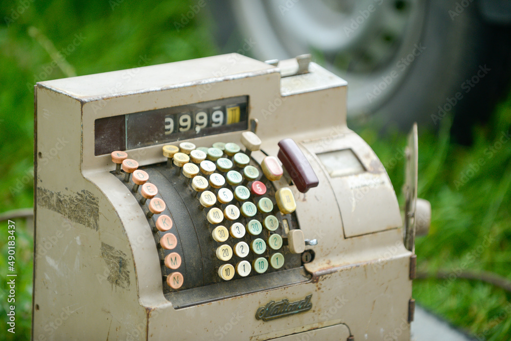 Sticker Closeup of a vintage dusty cash register with the background of  a tire and grass