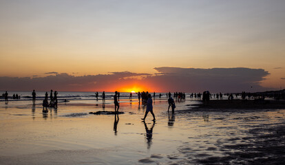 	 People gathered on the beach watching the sunset on a beautiful summer day