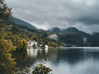 House surrounded by a beautiful lake and trees under a gray cloudy sky in Geretsried