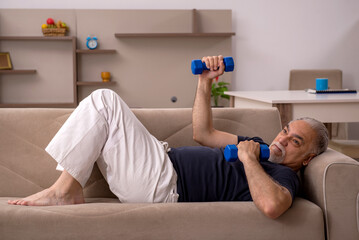 Old man doing sport exercises at home