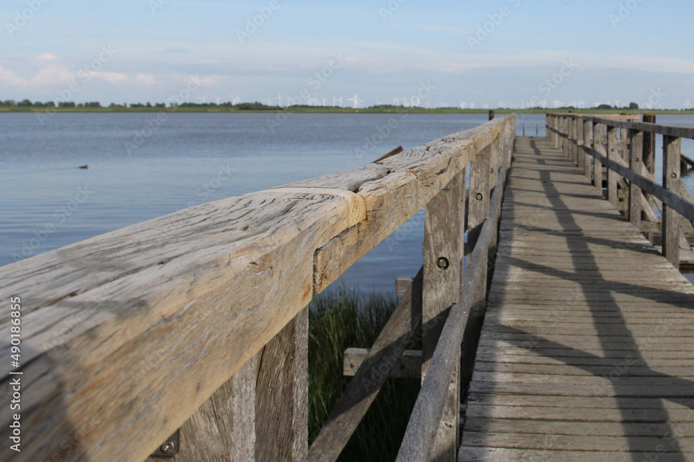 Sticker scenic view from the wooden dock of a lake and wind turbines on the horizon