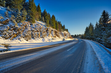 Traffic road passing through the dense forest on a cold snowy day