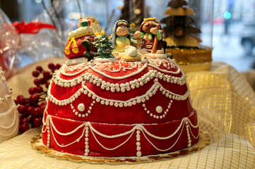 Closeup of a red cake with tiny cartoon figures and white decorations