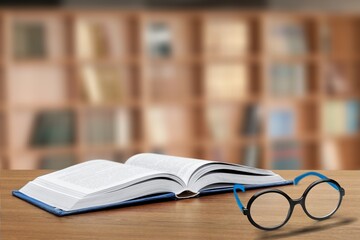 Old books, reading glasses on the wooden desk