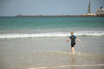 Young boy in a swimming suit ready to swim in Portland, Victoria, Australia