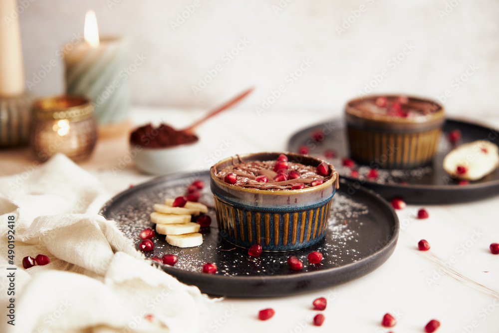 Sticker selective focus of a lava cake decorated with pomegranate seeds and banana slices on a black plate