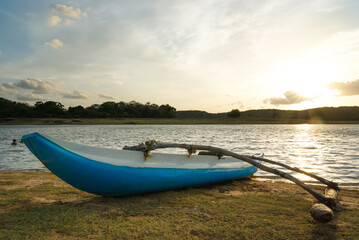 Traditional catamaran fishing boat ashore at sunset
