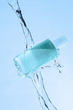 Vertical Shot Of A Blue Beauty Product Under The Running Water On A Blue Background