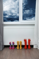 Rubber boots near heating radiator in room