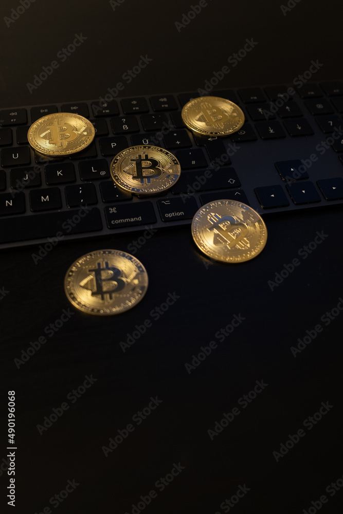 Poster vertical shot of bitcoins on a keyboard and dark surface - e-commerce concept