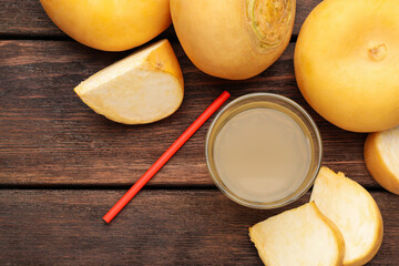 Glass of freshly made turnip juice on wooden table, flat lay