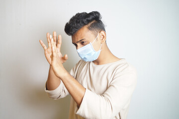 Young Indian guy wearing a protective mask in a defensive gesture against a white background