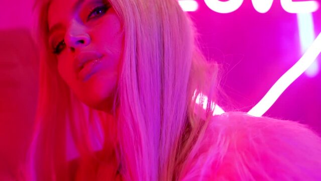 sexy blonde lady in pink neon lights in bordello or love hotel, love and passion