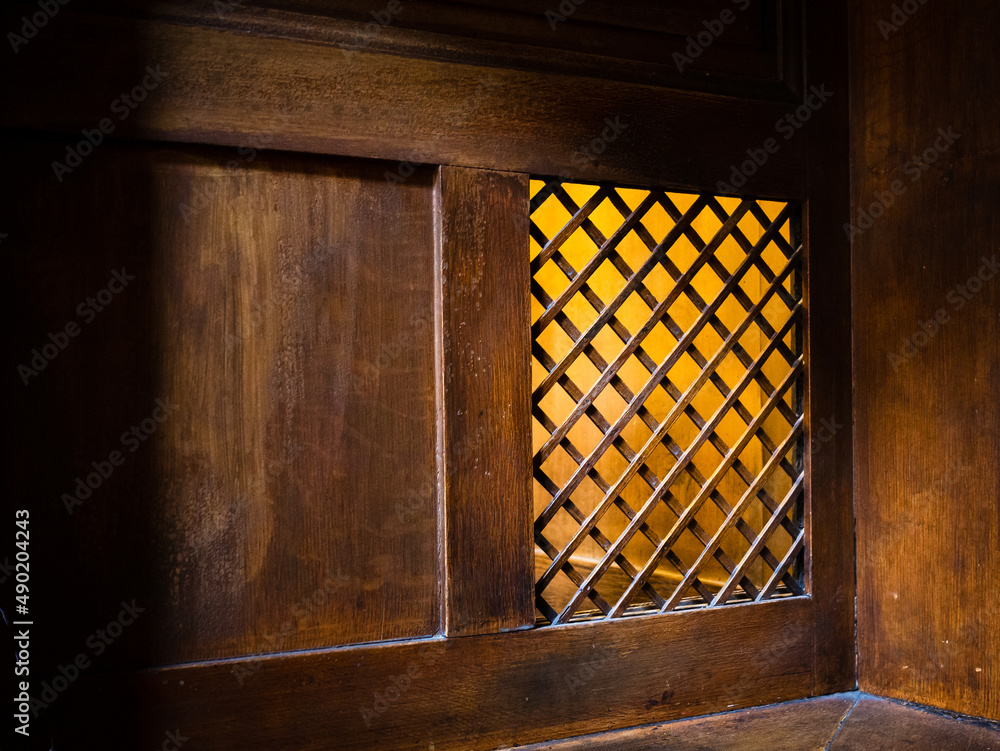 Sticker closeup of a wooden window of the confessional box at church