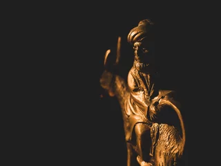 Foto auf Acrylglas Antireflex Closeup of a golden sculpture of Nasreddin Hodja riding a donkey backwards © Papace/Wirestock