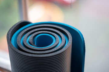 detalle de dos colchonetas, esterillas o mat de yoga enrolladas a la luz de la ventana, azul y gris