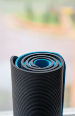 Fototapeta na wymiar detalle de dos colchonetas, esterillas o mat de yoga enrolladas a la luz de la ventana, azul y gris